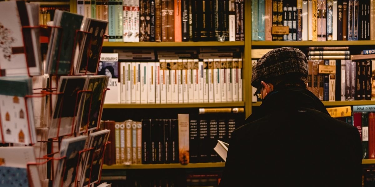 A person thoughtfully browsing through bookshelves, searching for their next captivating read.