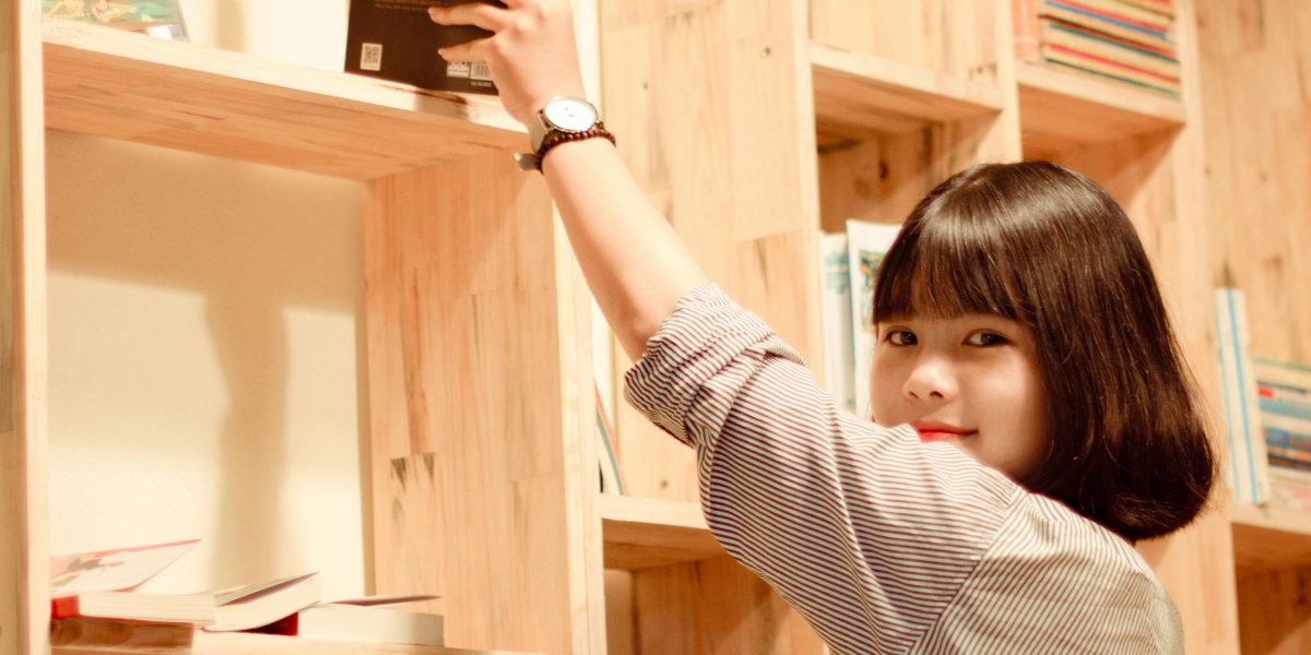 A person thoughtfully browsing a bookshelf, reflecting the search for their next great read.