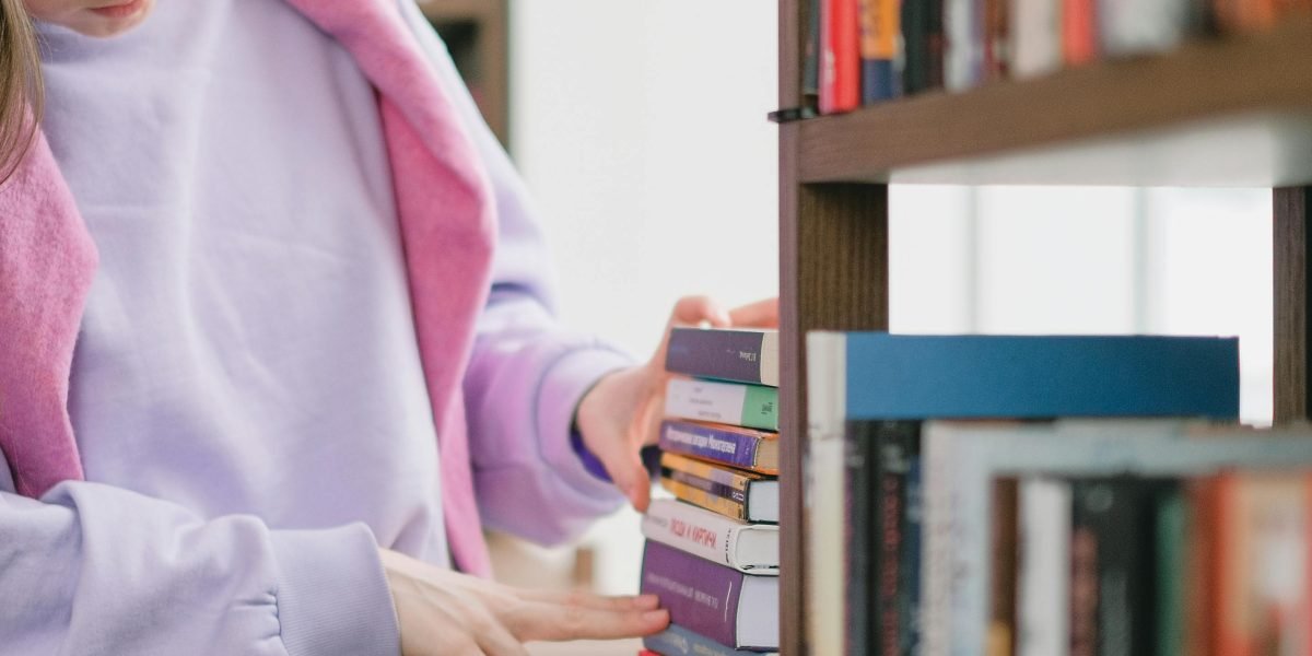 A child making a selection from a shelf full of books, guided by curiosity.