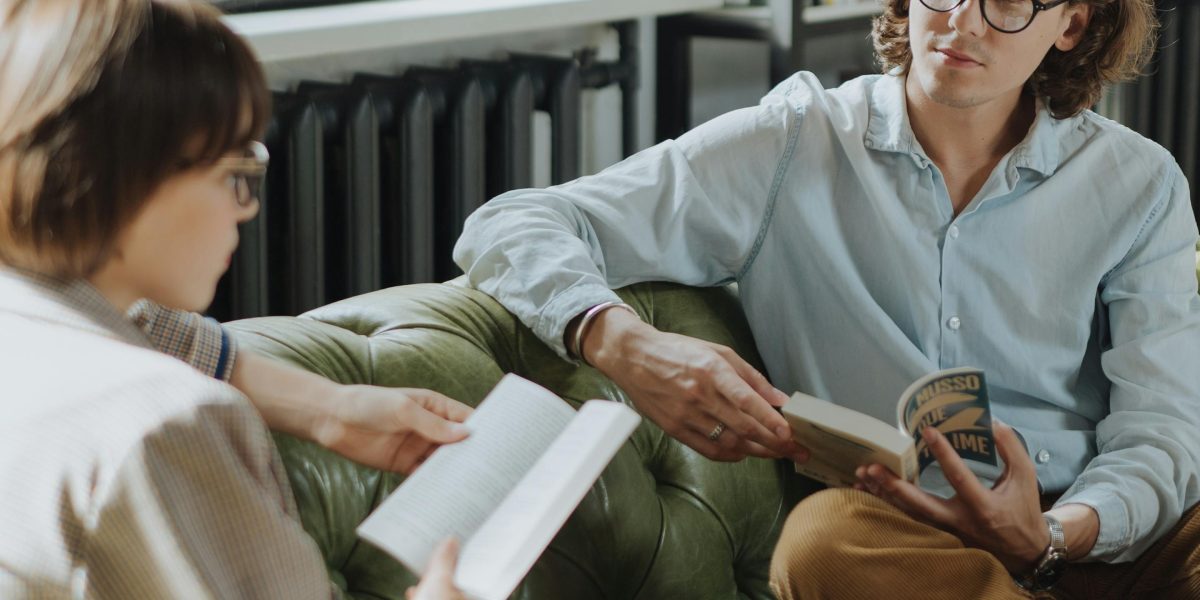 A group of people actively discussing a book in a relaxed book club setting.